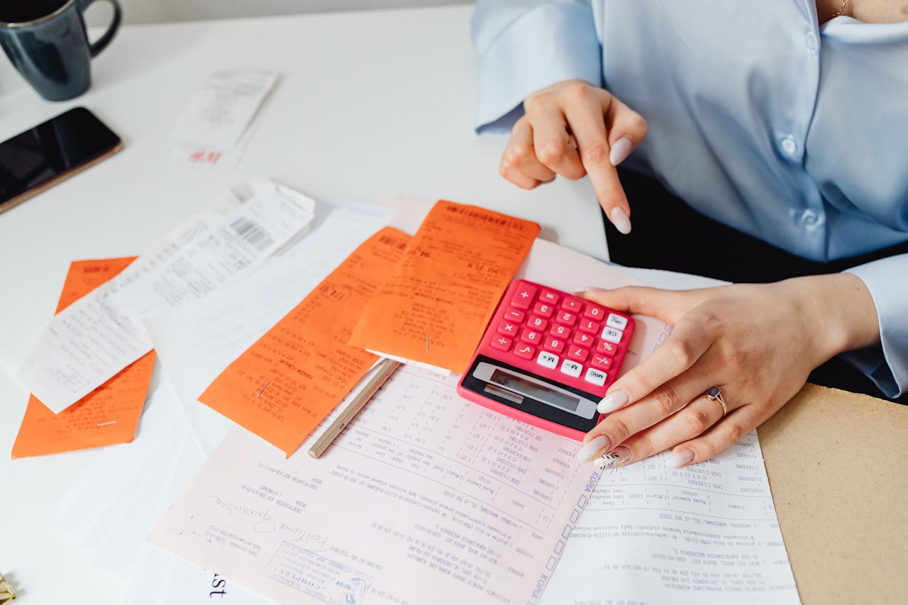 Businesswoman calculates expenses using receipts and calculator at desk. Ideal for finance, accounting themes.